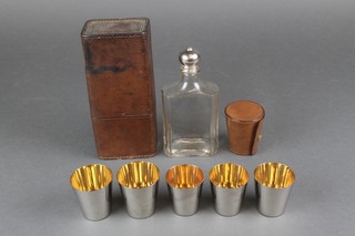 A glass flask contained in a leather case with 5 silver plated beakers and a leather carrying case 
