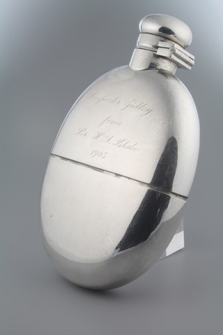 A Continental white metal hip flask with cup base and presentation inscription 