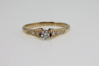 An 18ct gold single stone diamond ring with 3 diamonds to each shoulder, size L