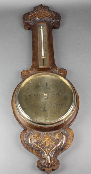 A 1920's aneroid barometer and thermometer with brass dial contained in a carved oak wheel case 