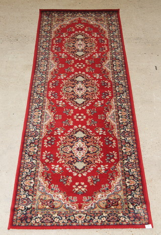 A Persian style red ground machine made runner 129" x 33"