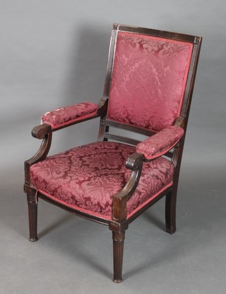 A Victorian mahogany open arm chair, the seat and back upholstered in red material, raised on turned and reeded supports 