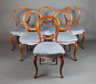 A set of 6 Victorian walnut balloon back dining chairs with carved mid rails, the seats of serpentine outline upholstered on blue dralon, raised on French cabriole supports 