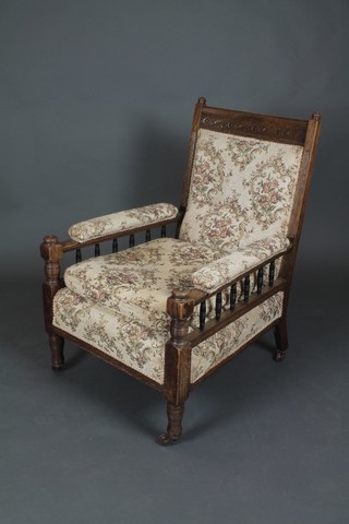 An Edwardian carved oak arm chair with bobbin turned decoration, the seat, arm and back upholstered in tapestry material, raised on turned supports