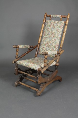 A 19th Century American beech framed rocking chair upholstered in tapestry material 