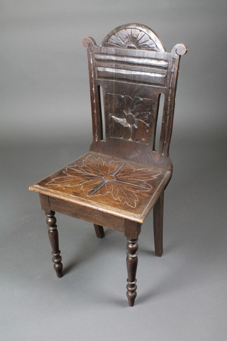 A Victorian carved oak arch shaped hall chair with solid seat and back, on turned supports