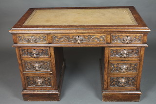 A carved oak kneehole writing desk with inset tooled writing surface above 1 long and 8 short drawers 28"h x 44"w x 23 1/2"d 