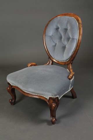 A Victorian mahogany show frame spoon back nursing chair upholstered in blue buttoned material, raised on cabriole supports 
