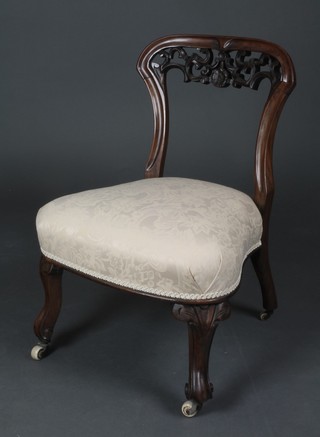 A Victorian rosewood pierced bar back nursing chair upholstered in white material, raised on cabriole supports  