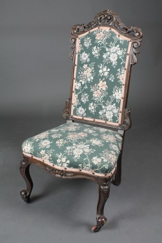 A Victorian carved mahogany nursing chair with upholstered seat and back of serpentine outline, raised on cabriole supports 