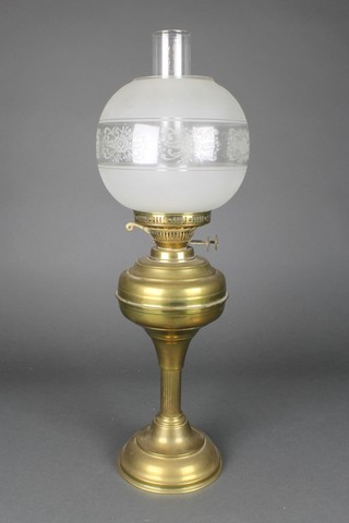 A brassed oil lamp base with etched glass shade and clear glass chimney