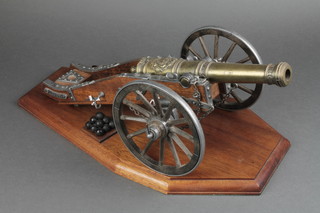 A model of Louis XVI canon with 10" barrel raised on a wooden and metal gun carriage having a mahogany base 