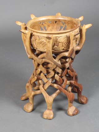 A circular "African" pierced and turned teak bowl, raised on a pierced and carved stand in the form of camels 19" x 17" 