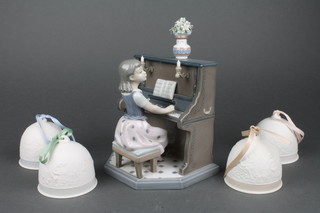A 1987 Lladro figure of a seated girl playing the piano, base incised 5462 9" together with 4 Lladro Collectors Society Christmas bells 1991-1994