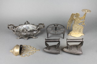 A brass candle holder in the form of a kneeling angel 8", a pierced brass holy water stoop, an Art Nouveau pewter boat shaped planter 10", a circular trivet and a pair of Silvester's flat irons 
