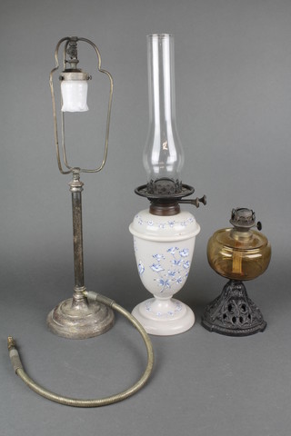 A Victorian engraved opaque glass oil lamp reservoir, an amber glass oil lamp reservoir raised on a pierced iron base and a gas table lamp 