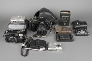 A Canon EOS camera with lens, a Minolta Hi-Matica AF2 camera, a Canon Z Sure Shot 90W camera, a pocket camera model B, a Fuji film digital camera F460, a pair of Miranda field glasses  