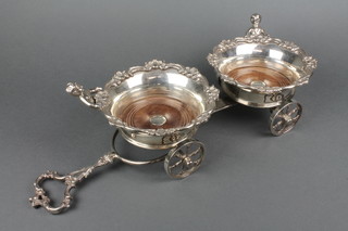 A silver plated 2 section table top coaster wagon with shell borders and figural handles with scroll handle and wheeled base 
