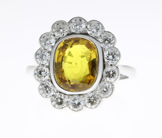 An 18ct white gold yellow sapphire and diamond cluster ring, the centre stone approx. 3.60ct surrounded by 14 brilliant cut diamonds approx. 1.2ct, size O 1/2