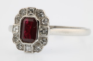 An 18ct white gold ruby and diamond cluster ring, the rectangular cut centre stone surrounded by 4 Princess and 8 brilliant cut diamonds 