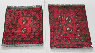 A pair of red ground Afghan slip rugs with octagons to the centre 24" x 19" and 27 1/2" x 19 1/2" 
