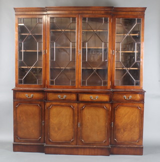 A Georgian style mahogany breakfront library bookcase, the upper section with moulded and dentil cornice, the shelved interior enclosed by astragal glazed panelled doors, the base fitted 4 short drawers above cupboards, raised on a platform base 78 1/2"h x 70"w x 17"d 
