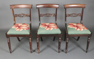 A set of 3 Georgian mahogany bar back dining chairs, the pierced mid rails carved acorns with upholstered drop in Berlin woolwork seats, raised on front turned and rear sabre supports  