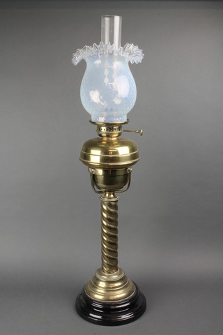 A Victorian brass oil lamp reservoir raised on a spiral turned column with vaseline glass shade and clear glass chimney