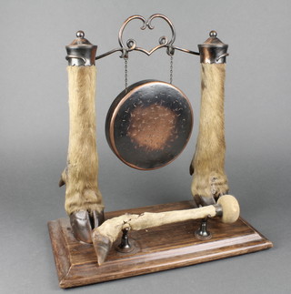 A copper tea gong supported by stuffed and mounted deers feet and with beater 