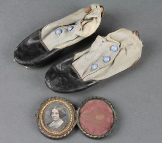 A pair of Victorian childs leather and cloth shoes, the base marked Kate's first boot 1864 5" together with a daguerreotype head and shoulders portrait of a lady 1 1/2" 