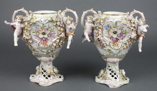 A pair of 19th Century German twin handled urns with floral decorated decoration supported by figures, raised on pierced bases 7 1/2" 