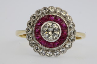 An 18ct yellow gold ruby and diamond target ring, the centre stone 0.4ct, size N 1/2