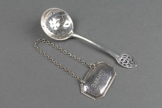 A silver sifter spoon and a spirit label 