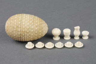 A 19th Century carved ivory ovoid box with geometric decoration 1 3/4" containing a miniature ivory tea set