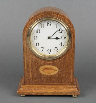 An Edwardian mantel clock with paper dial and Arabic numerals contained in an inlaid oak arch shaped case on bun feet 