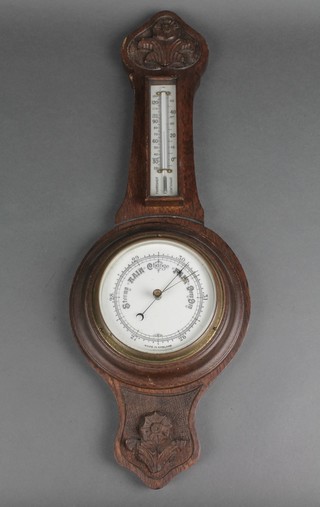 A 1920's aneroid barometer and thermometer  with enamelled dial contained in a carved oak wheel case 