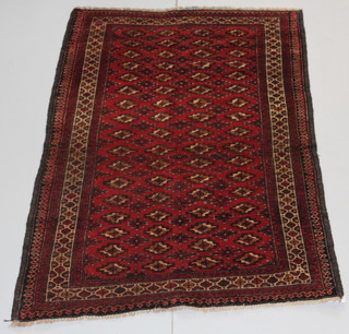 A Persian Balochi red ground rug with numerous gulls and medallions to the centre within multi-row borders 73" x 43" 