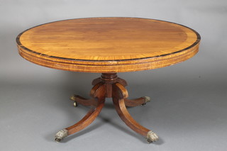 A Regency circular mahogany snap top breakfast table, crossbanded with satinwood and rosewood, raised on a gun barrel turned column and tripod base ending in brass paw feet 20 1/2"h x 51"diam.  