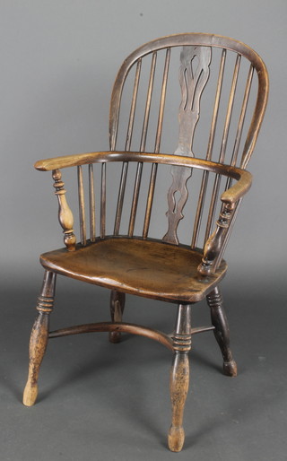 A 19th/20th Century elm Windsor armchair raised on turned supports with crinoline stretcher 