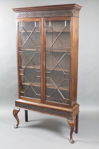 An Edwardian Chippendale style mahogany bookcase with moulded cornice and blind fret work frieze, the interior fitted adjustable shelves enclosed by astragal glazed panelled doors, raised on cabriole supports 76"h x 39"w x 12"d
