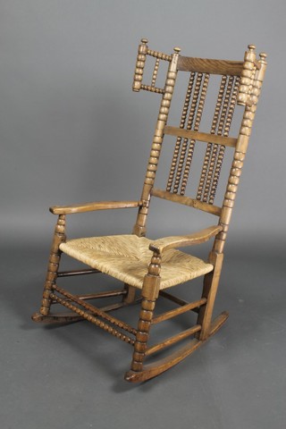 An elm rocking chair with bobbin turned decoration and woven rush seat