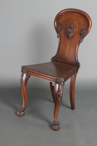 A Victorian mahogany hall chair, the shaped back with carved armorial and solid seat, raised on cabriole supports 