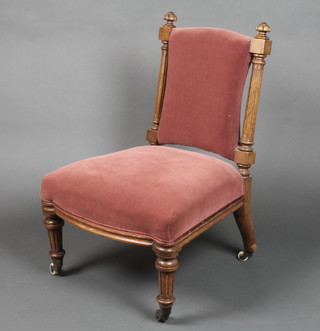 A Victorian walnut show frame nursing chair, having turned and fluted columns to the side, raised on turned and fluted legs, with upholstered seat and back 