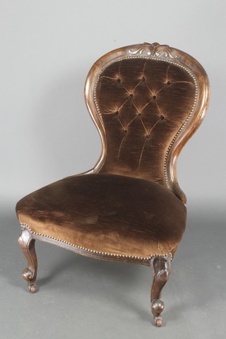 A Victorian carved mahogany show frame nursing chair upholstered in brown buttoned material, raised on cabriole supports together with a similar balloon back chair with carved mid rail on cabriole supports 