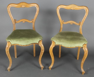 A pair of bleached mahogany buckle back dining chairs with carved mid rails, the seats of serpentine outline, raised on cabriole supports 
