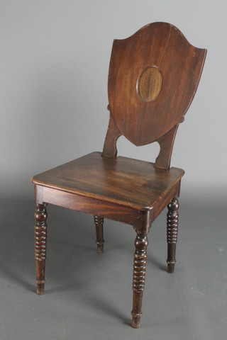 A 19th Century mahogany shield back hall chair with solid seat raised on ring turned supports