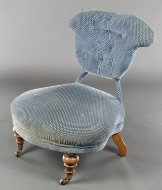 A Victorian iron framed nursing chair upholstered in blue buttoned material, raised on turned supports 