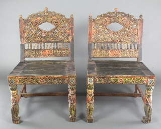 A pair of 19th/20th Century Indian carved and pierced hardwood chairs with solid seats and carved backs, raised on figural supports 