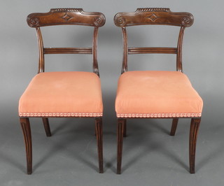 A pair of William IV mahogany bar back dining chairs with carved mid rails and upholstered seats, raised on sabre supports 