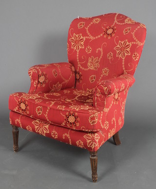 A Victorian style armchair upholstered in red material raised on turned and fluted supports